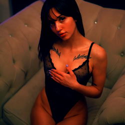 Pragtige vrou in 'n swart eenstuk in die donker