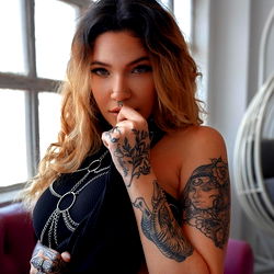 Pragtige vrou met tatoeërings in 'n sensuele posering